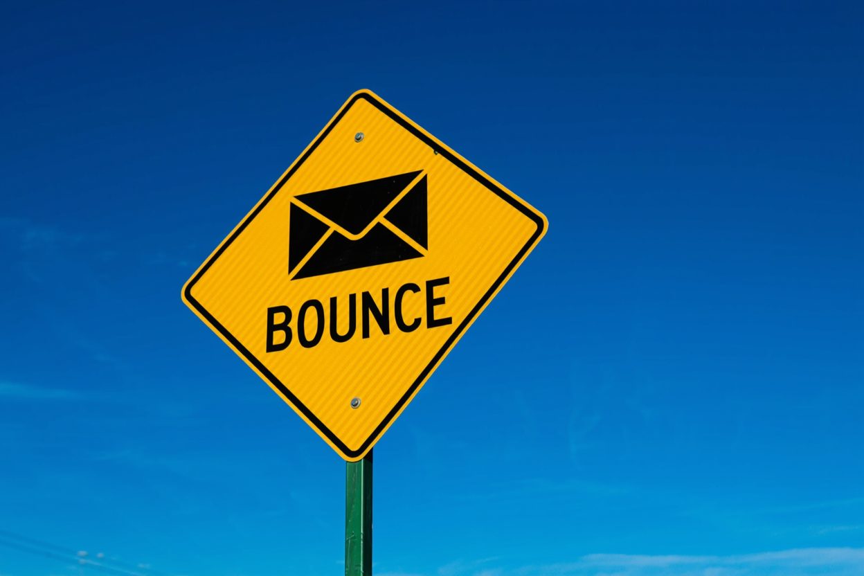 A yellow diamond road sign reading BOUNCE with an envelope icon, against a clear blue sky